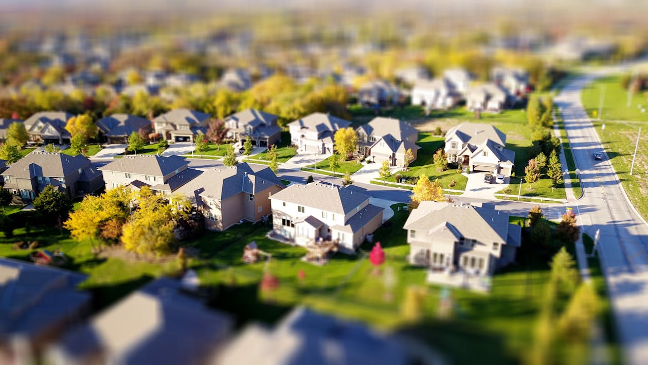 Professional, moody photograph of a 'For Sale' sign in front of a modern suburban home, symbolizing the negative effect of...